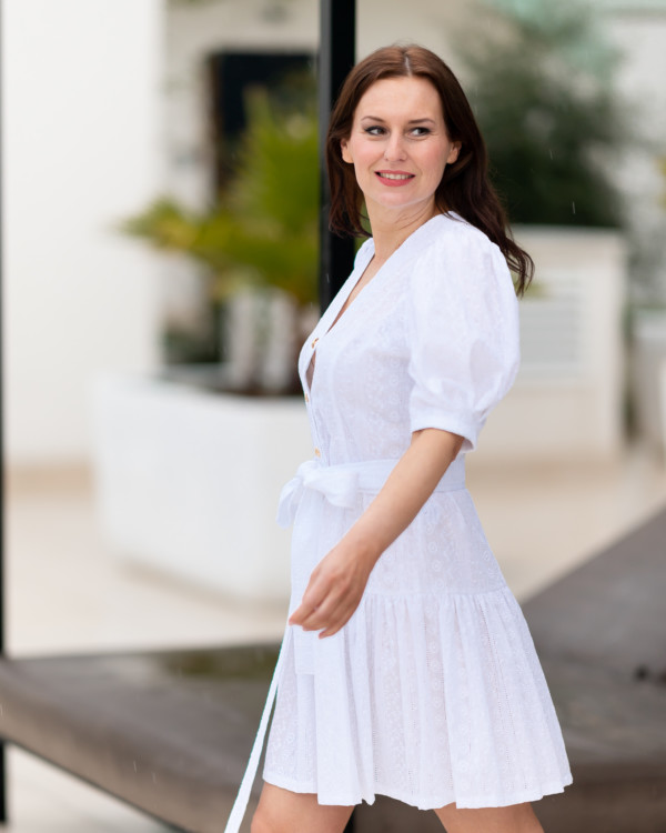 Žena v bielych madeirových šatách od značky Love Colors kráča na ulici