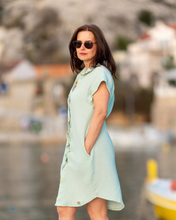 Žena v mintových mušelínových šatách košeľového strihu pózuje v prístave