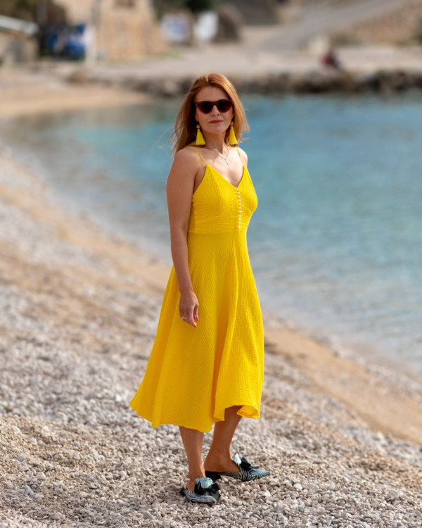 Žena v žltých šatách od Love Colors pózuje pri mori
