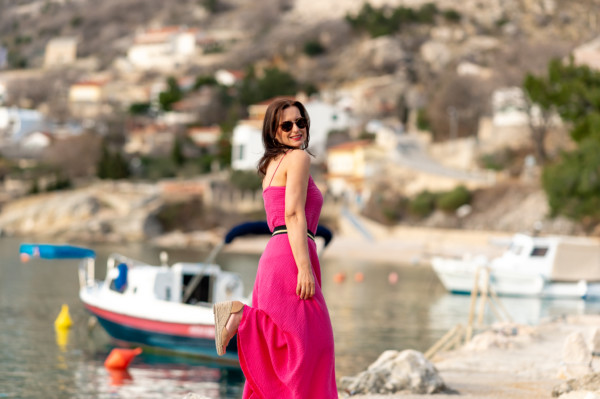 žena v mušelínovom oblečení značky Love Colors magentovej farby pózuje pri mori