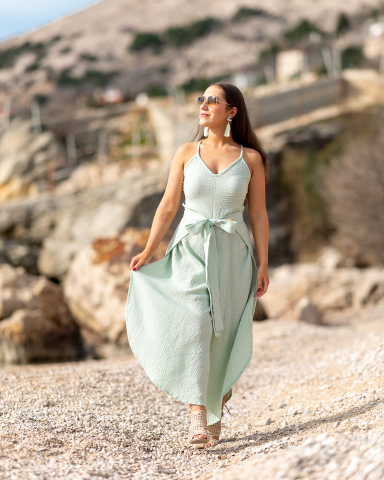 Žena v mintovom mušelínovom oblečení značky Love Colors kráča pri mori